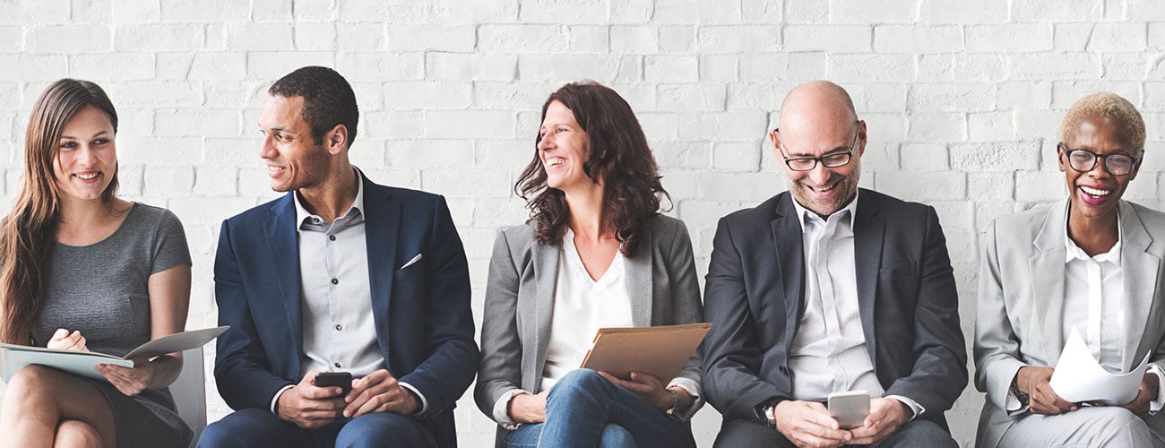 Business people sitting along a wall