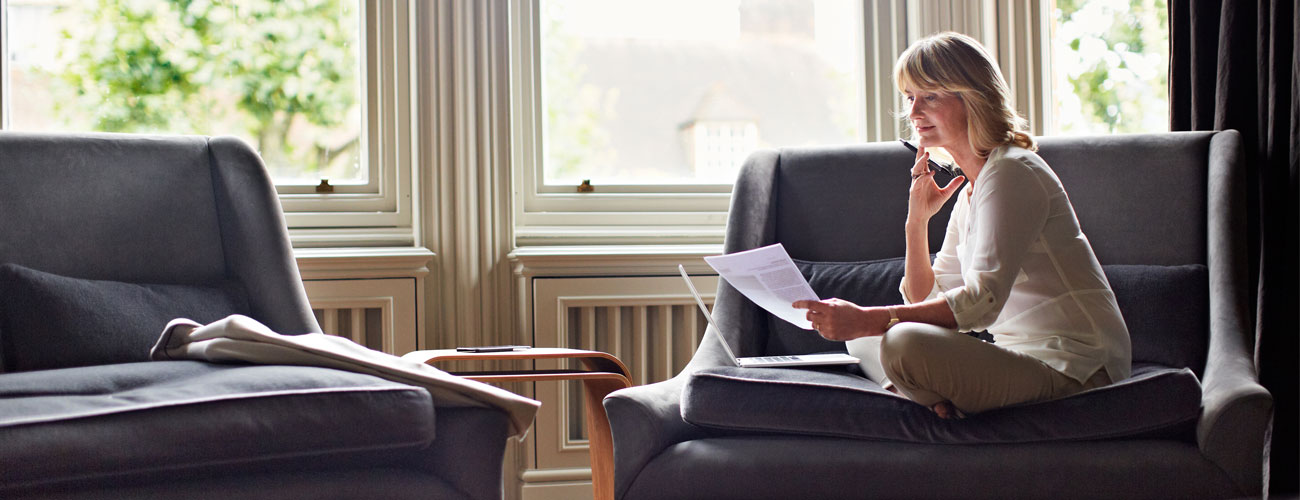 Woman sitting on a chair with a pen looking over paperwork